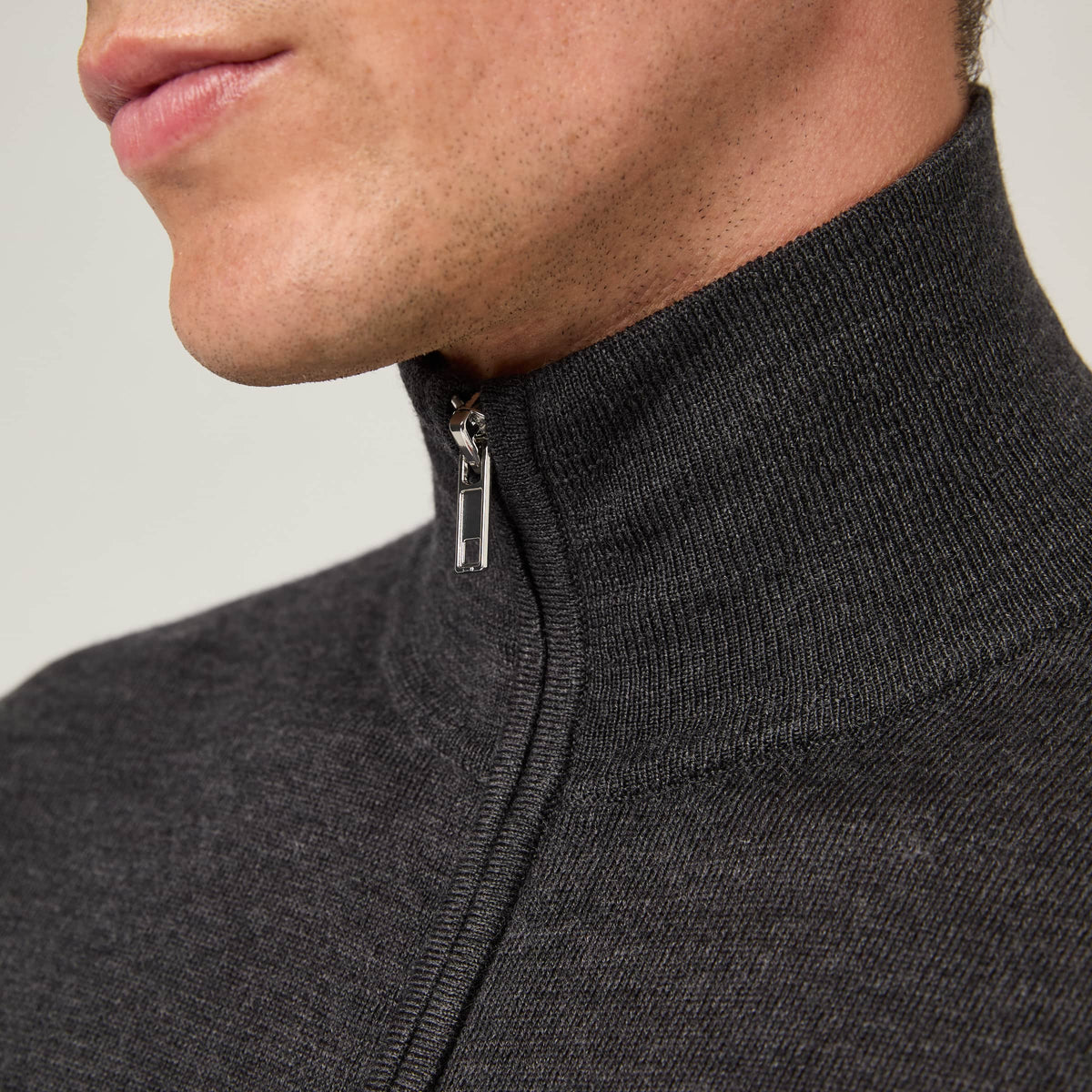 Close-up of the high ribbed collar and metal zipper on the Men's Merino Full Zip Cardigan in Dark Grey Melange.